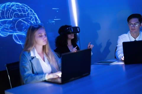 Group of young professionals in a tech workspace using laptops and virtual .. Stock Photos