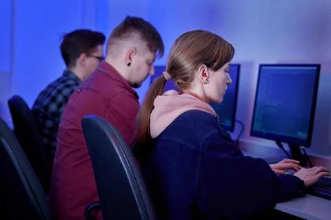 A group of young programmers work in an office at a computer. Stock-Fotos