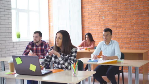A group of young students sitting in the classroom and listening attentively to Stock Footage 86750685