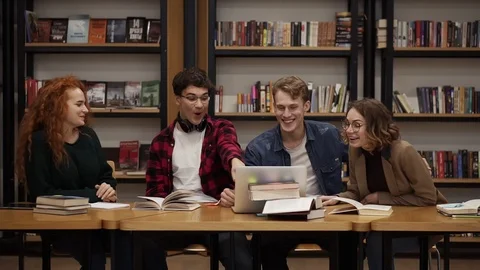 Group of young students talking using laptop explaining course work study Stock Footage 122560617