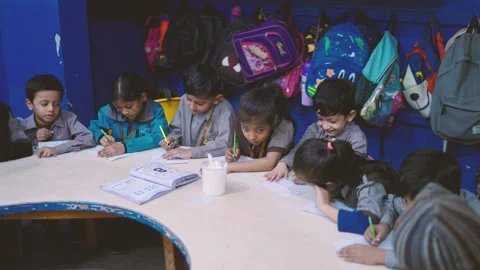 Group of young students writing and drawing at a classroom table in Karachi Stock Footage 329222105