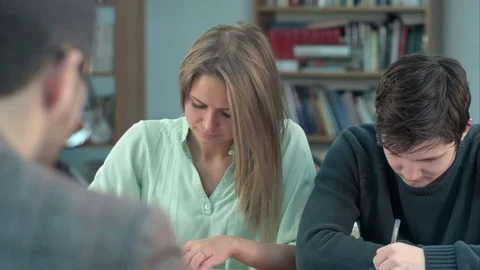 Group of young students writing something in their note pads while sitting in a Vídeos de archivo 77507613