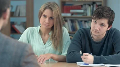 Group of young students writing something in their note pads while sitting in a Stock Photos