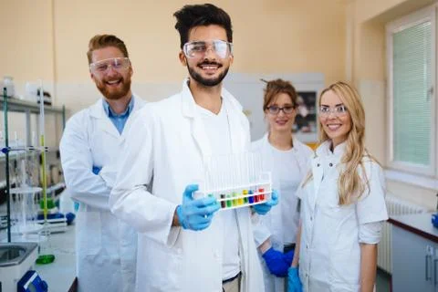 Group of young successful scientists posing for camera Stock Photos