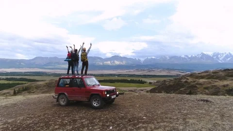 A group of young travelers stands by the car in the background of a mountain Stock Footage 79710153