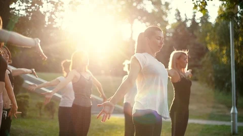 Group of young women are together practicing yoga in the park while sunrise Stock Footage