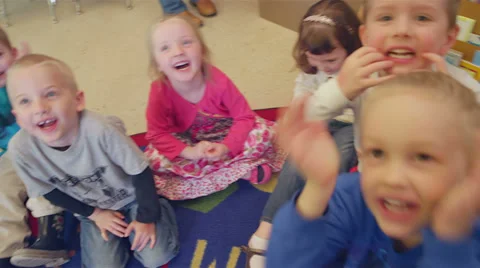 A group of younger children sit in a circle on the floor making funny faces Stock Footage 34004925