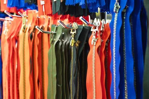 Group of zippers hangs on rack with hooks at exhibition Stock Photos