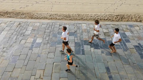 Groups of four runners on the stone waterfront by the beach. 库存影片 93860137