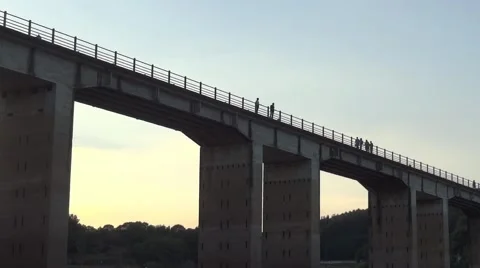 Groups of people walking on a tall bridge built over a deep valley Stock Footage 62692065