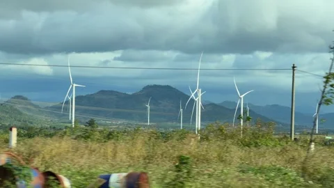 Groups of wind turbines rise above rolling green hills beneath heavy clouds Stock Footage 324839014