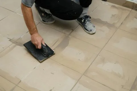 Grouting ceramic tiles, close up. Putting fugue on tiles on the floor Stock-Fotos