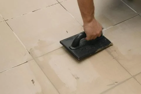 Grouting ceramic tiles, close up. Putting fugue on tiles on the floor Photos
