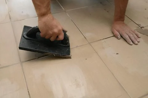 Grouting ceramic tiles, close up. Putting fugue on tiles on the floor Photos