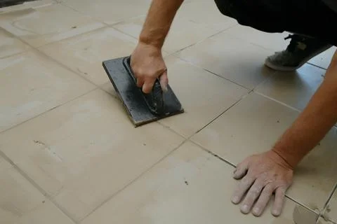 Grouting ceramic tiles, close up. Putting fugue on tiles on the floor Stock-Fotos