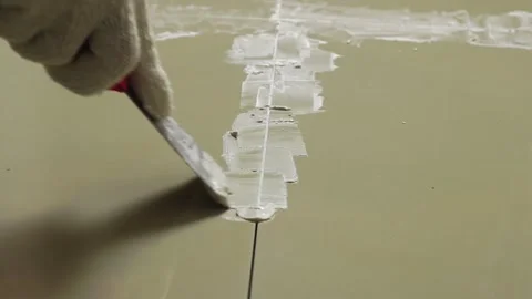 Grouting ceramic tiles. Tilers filling the space between tiles using a Stainless Stock Footage 171763423