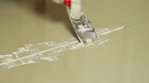 Grouting ceramic tiles. Tilers filling the space between tiles using a Stainless Stock Footage 171763424