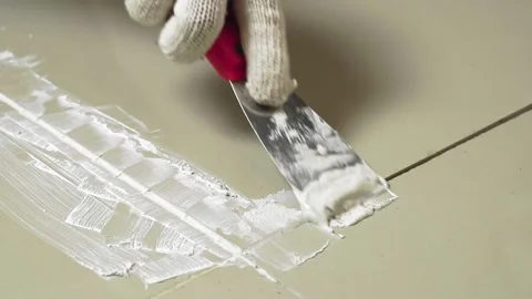 Grouting ceramic tiles. Tilers filling the space between tiles using a Stainless Stock Footage 171763447