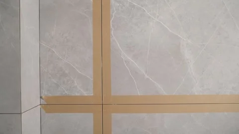 Grouting process on grey marble look porcelain tiles on a wall corner during Stock Footage 344906179
