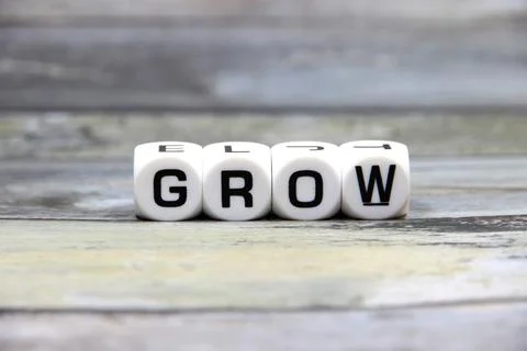 "GROW" text or message short word letter on white plastic block with wood p.. Stock Photos