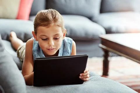 Growing up as one smart young kid. a little girl using a digital tablet at home. Stock Photos