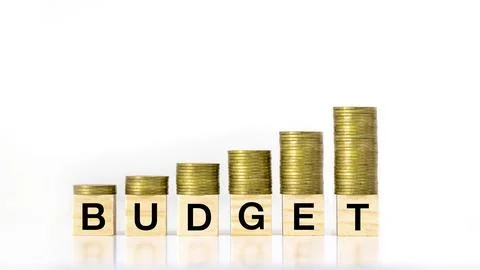A growing stack of coin steps on a wooden block labeled budget on a white b.. Stock Photos