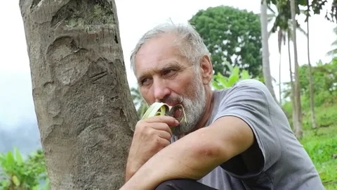 A grown man eats a banana. Video stock 137554899