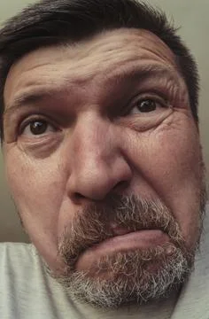 A grown man with gray stubble makes faces. Grimaces in front of the camera Stock Photos