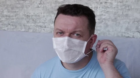 A grown man takes a medical mask and smiles looking into the camera. Stock Footage