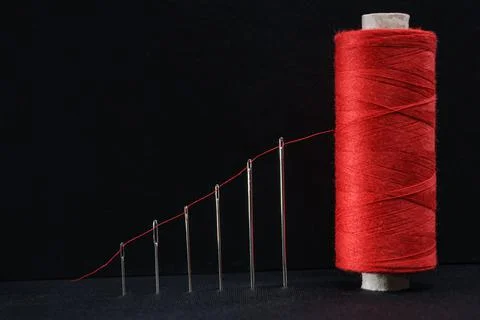 Growth graph as a red thread passed through a sewing needle to a spool Stock Photos