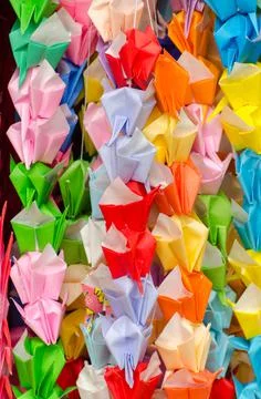 Grullas de papel colorido u origami colgadas de un arbol como decoracion en e Stock Photos