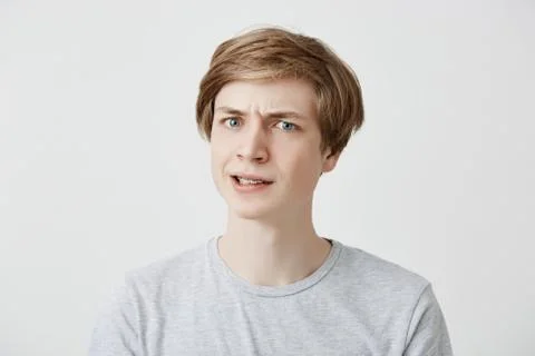 Grumpy irritated fair-haired young male being emotional and angry after offended Stock Photos