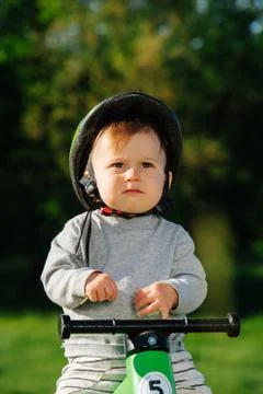 Grumpy little kid sitting on a three-wheel foot bike Stock Photos