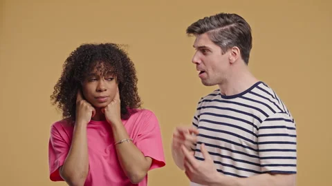 Grumpy man scolds on african american woman. Irritated girlfriend covered ears Stock Footage 314109574