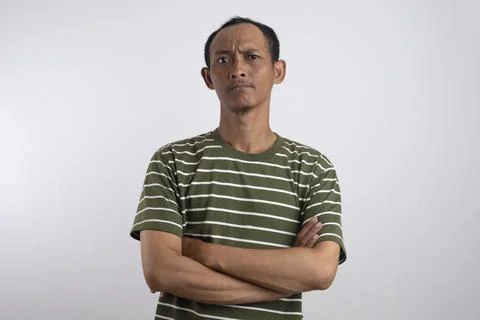 Grumpy mature man with crossed arms is judging and feeling skeptical about .. 库存照片