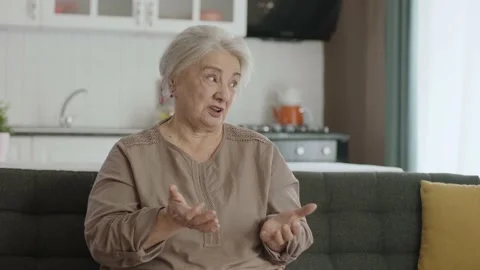 Grumpy old woman sitting on sofa at home. Stock Footage 190020465