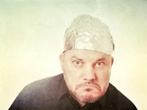 Grumpy paranoid man wearing tin foil hat Foto stock