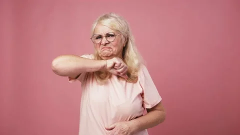 Grumpy senior woman looking at camera and gesturing thumb up gesture, pink Stock Footage 145353998