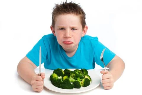 Grumpy young boy not happy about eating broccoli. Foto stock