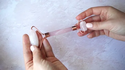 Gua Sha massager jade roller in female hands. Pink jade stone Stock Footage 150259391