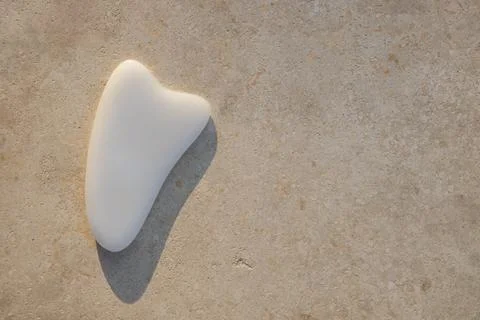 Gua sha scraper white agate massager on light textured surface, sunset light, Stock Photos