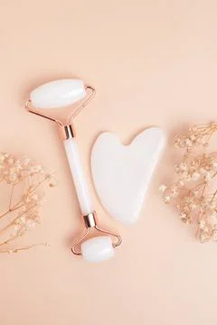 Gua sha stone, face roller for face massage on a beige background Stock Photos