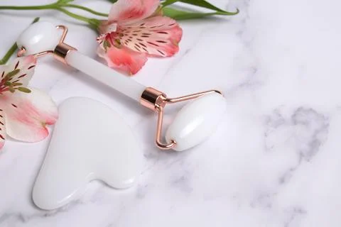 Gua sha stone, face roller for face massage on a marble background Stock Photos