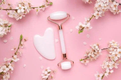 Gua sha stone, face roller for face massage on a pink background with Stock Photos