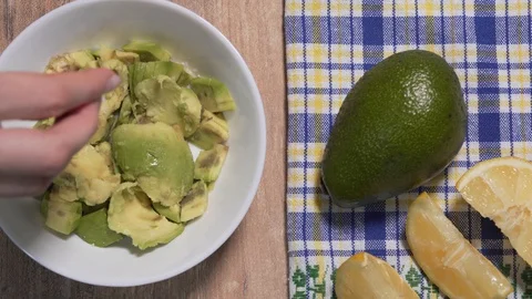 Guacamole recipe, second step. The lemon is squeezed into the avocado pulp in a Stock Footage 125711365