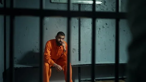 Guard holding baton, intimidating inmate behind bars, strict prison control Stock Footage 319009943