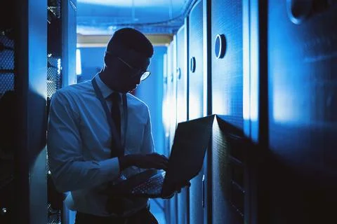 Guarding your data. a young man working in an IT server room. 스톡 사진
