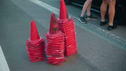 Guards cones are stacked in separate piles on the track next to the sports car 動画素材 148321816
