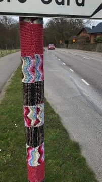 Guerilla knitting on a pole with a car in the background. Stock Photos