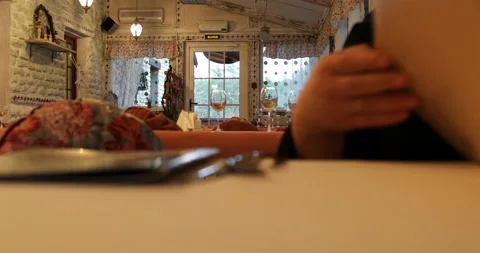 The guest of the cafe is examining the menu, sitting at the table Stock Footage 106171327